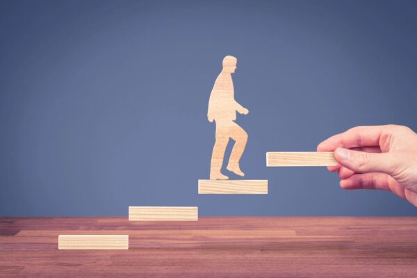 Wooden figure climbing steps with assistance.